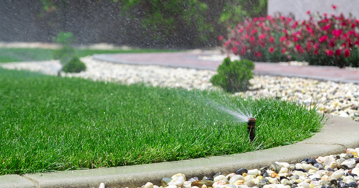 Sprinkler system misting water over green lawn